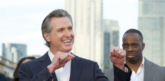 Smiling man giving a speech at an outdoor event.