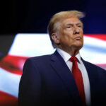 Sinatra Feud Explodes Over Trump “My Way”… donald trump in suit with red tie American flag backdrop