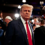 WEAPONIZED Sports—Trump’s Envoy Stuns FIFA Officials… A serious-looking man in a suit with a red tie surrounded by a crowd and cameras