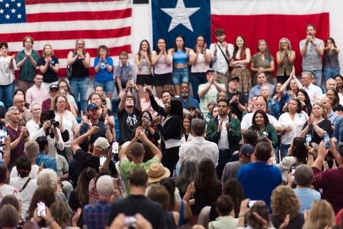 shutterstock_2682332445.jpg A large crowd at a political rally with people cheering and taking photos