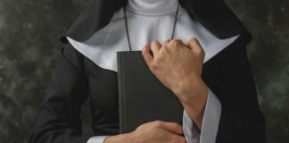 A nun in traditional attire holding a book close to her chest
