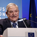 Soros DA Hits ICE Agent — Feds Erupt…. Older man speaking at a podium during an economic forum
