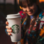 VIDEO: Starbucks’ ‘Tank Day’ Sparks National Outrage… Starbucks cup held by a smiling person outdoors