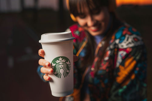 shutterstock1669745779jpg Starbucks cup held by a smiling person outdoors
