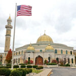 NEO-NAZI Attack’s Shocking HERO – Who Saved Kids? A mosque with a golden dome and minarets, featuring an American flag in front