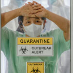Ebola OUTBREAK Kills 65—Porous Borders Threaten Globe… A healthcare worker in a green uniform and mask, looking distressed behind a glass door marked with quarantine signs