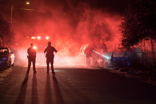 Police officers on a street surrounded by smoke and emergency lights