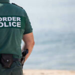 Border Powers Reach Far Inland Border police officer standing near water.