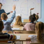 Parental Rights Shake California’s Schools Students raising hands in a classroom as a teacher leads a lesson