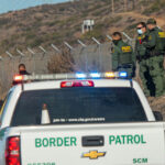 Cartel Violence Erupts Near U.S. Routes Border Patrol agents gather near trucks by a fence