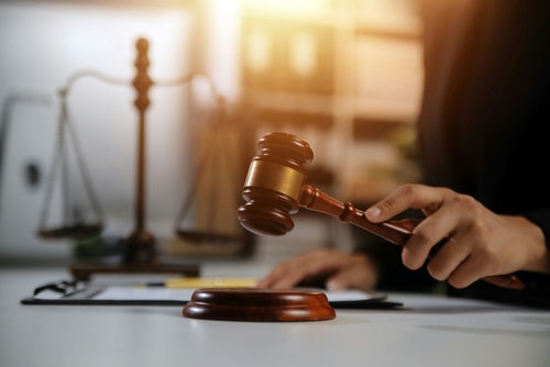 shutterstock2478909667-1jpg Judge's hand striking a wooden gavel on a sound block