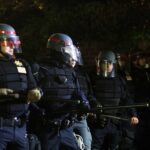 Stray Bullet Turns Bar Crawl Bloody Police officers in riot gear standing in formation at night