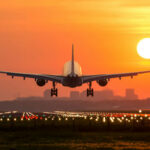 Runway Close Call Exposes FAA Blind Spot Airplane landing at sunset on illuminated runway.