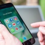 UK Ban Could Change Internet Forever Person holding smartphone with social media app folder open