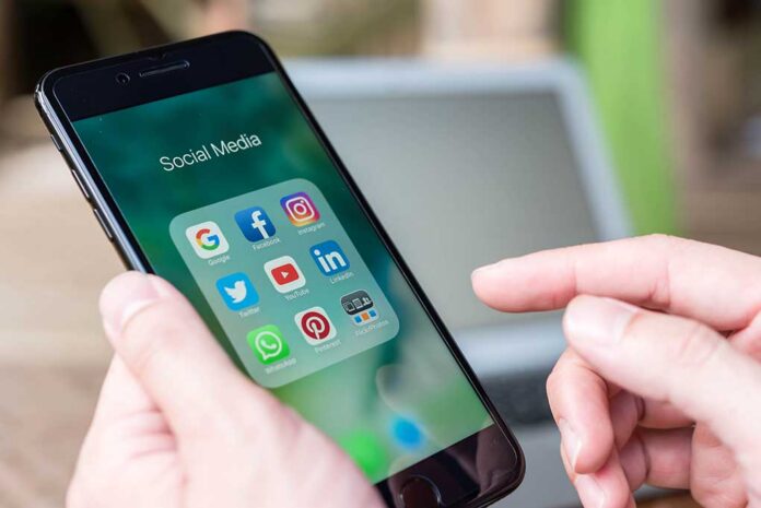 Chiang,Mai,,Thailand,-,November,14th,,2016:,Hand,Of,Man Person holding smartphone with social media app folder open