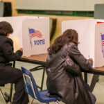 Ballot Scandal Triggers Deportation Fears People voting in booths at a polling station.