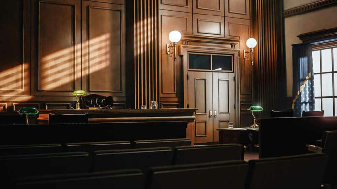 2056420763 Empty courtroom with sunlight streaming through windows.