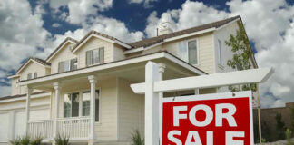 House with For Sale sign in front yard.
