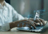AI Boom Fuels New Inflation Fears Hands typing on laptop with AI holograms.