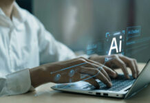 AI Boom Fuels New Inflation Fears Hands typing on laptop with AI holograms.