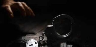 Handcuffs on cash with a reaching hand in low light