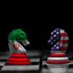 Iran Deal Already Showing Cracks Chess knights with Iran and USA flags facing each other on a board