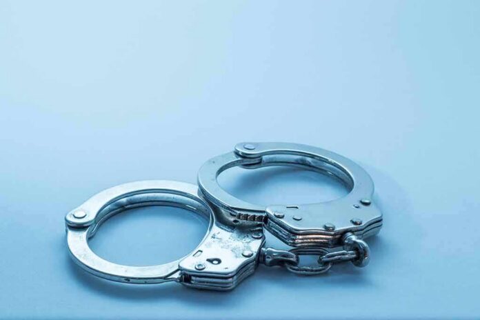 shutterstock_1098085049 Metal handcuffs on a light blue surface
