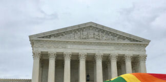 Supreme Court building with rainbow flag in foreground.