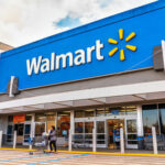 Are Walmart Prices Really Falling? Walmart storefront with people and shopping carts outside.