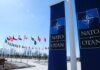 NATO flags displayed at the headquarters under a clear blue sky