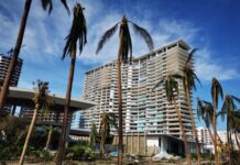 Category 5 Typhoon Devastates U.S. Island Damaged residential building surrounded by palm trees after a storm
