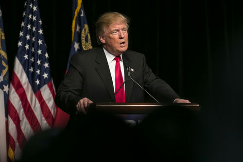 shutterstock_403318102 Donald Trump speaking at event with American flags.