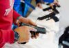 Person holding and inspecting a handgun at display.