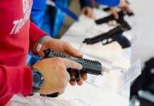 Person holding and inspecting a handgun at display.