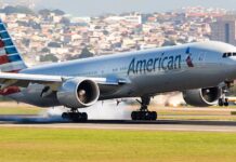 Airplane landing on runway with city in background.