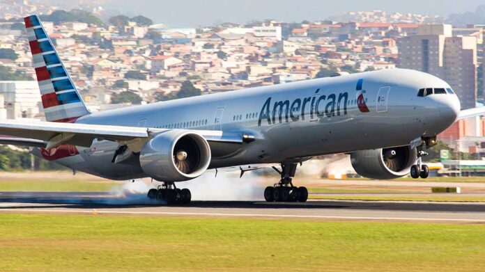 Airplane landing on runway with city in background.