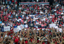 A large crowd at a political rally with signs.