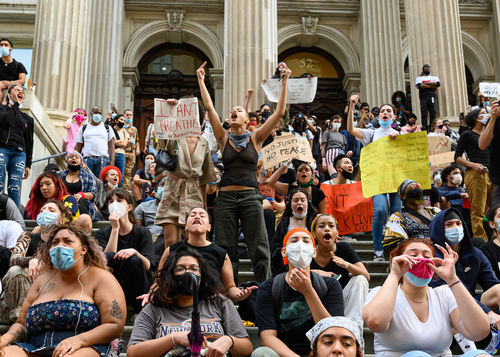 Protesters holding signs and chanting on courthouse steps.