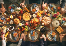 Thanksgiving feast with people holding hands around table.