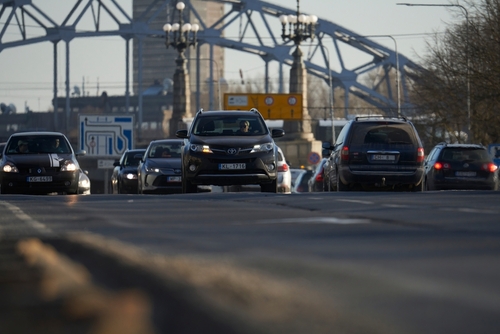 Cars driving on a road with bridge background.