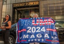 People holding Trump 2024 MAGA banner outside Trump Tower.