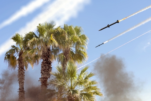 Missiles flying over palm trees with smoky sky.